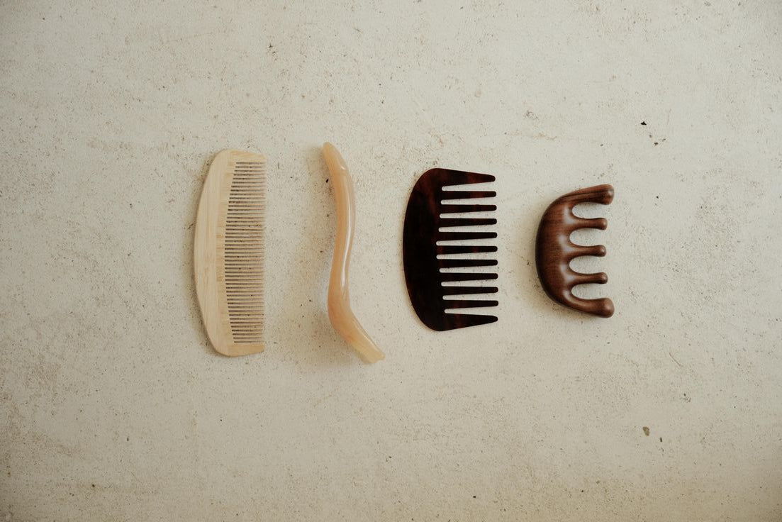 Set of wooden grooming tools including a comb, brush, and other items on a textured beige surface.